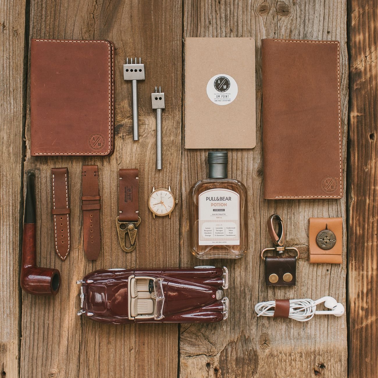 Flat lay of leather accessories and small collectibles on wood
