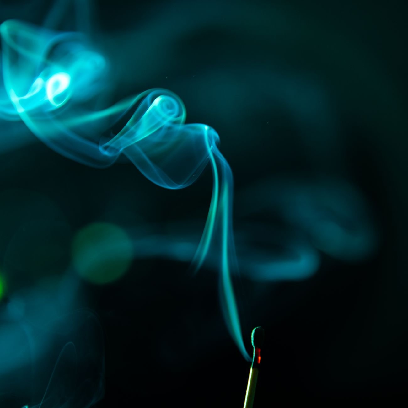 Close-up of a lit match with smoke rising against dark backdrop